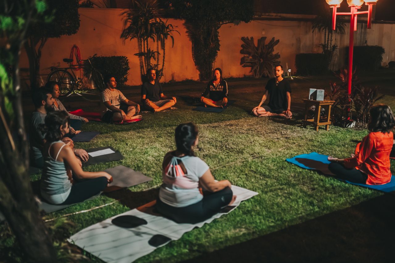 Group practicing yoga outdoors at night for relaxation and wellness.