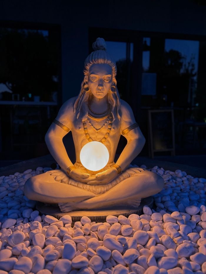 Crafting Captivating Headlines: Your awesome post title goes here A serene sculpture of Shiva holding an illuminated orb, surrounded by pebbles.